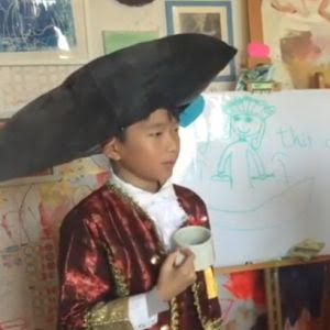 A young student dressed in a colonial period costume holds a cup of tea