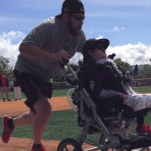 A bearded man pushes a wheel chair while running