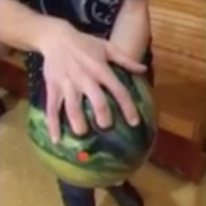 Fingers are properly placed in the holes of a green bowling ball