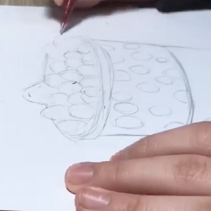 A close-up shot shows a pencil drawing of a cup with circles inside and piled up on top.