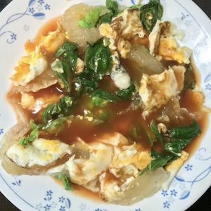A finished and plated dish shows eggs, oysters, greens, all in a broth.