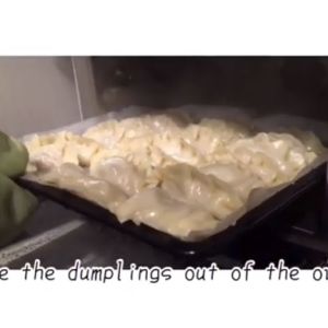 A sheet pan full of dumplings is pulled out of an oven