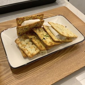 Four cookies of softened marshmallows squished between two crackers are displayed on a plate