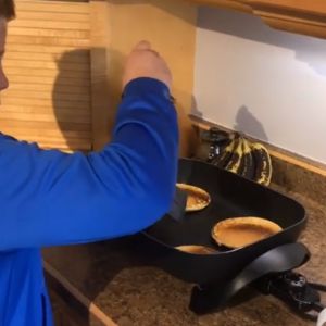 Someone flips pancakes in an electric griddle.