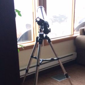 A telescope points out a window