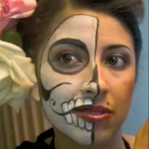Half of a woman's face is painted as if it were a skull