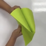 A close up of hands folding a neon green piece of paper