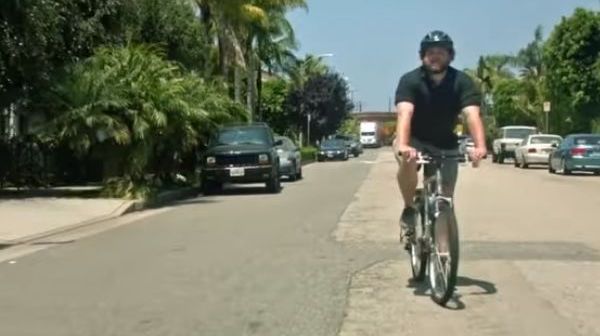 A man rides a bike on the side of the road