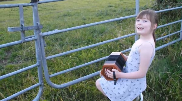 Girl playing a musical instrument while cows watch