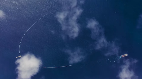 A long container in the ocean with captured plastic garbage