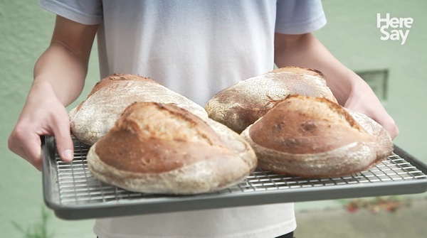 Boy holding a pan with four loaves of sourdough bread