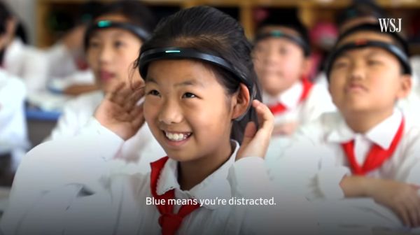 A young girl smiles as she holds onto a black plastic band around her head