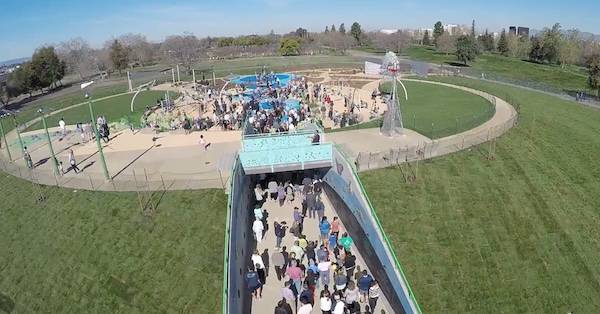 A drone shot from above a crowd waiting to enter a new playground/park.