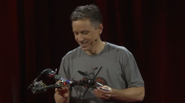 A man looks down at a drone he's holding in his hands