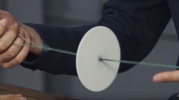 man pulling two sides of a string to make a piece in the center rotate