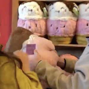 One person hands a stuffed toy to another person