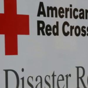 A close up of a sign shows the Red Cross logo