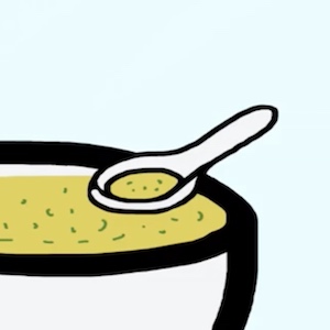 A spoon holds some green soup