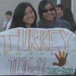 Two students hold a hand-drawn sign promoting a turkey drive