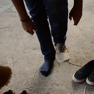 A person tries on a new pair of shoes, with his leg up in the air as he tries to tie the laces of that shoe.