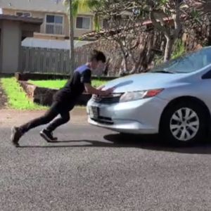 A boy pushes a car