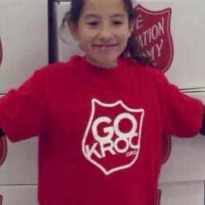 A young girl smiles while wearing a red 