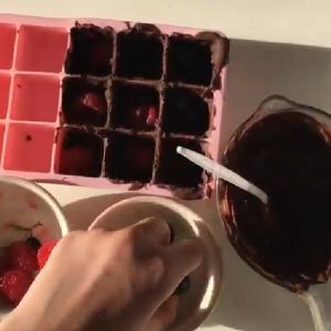 Strawberries and melted chocolate in an ice tray